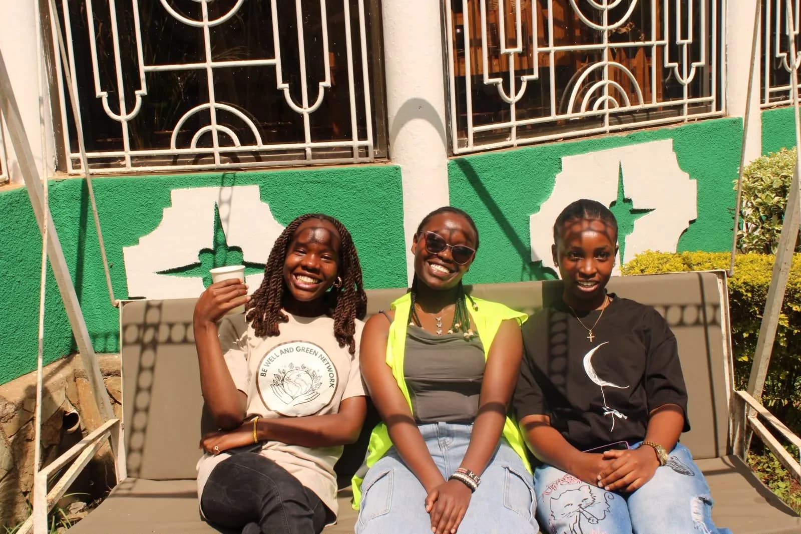 Three young women, one wearing a BWGN T-shirt, sitting together outdoors