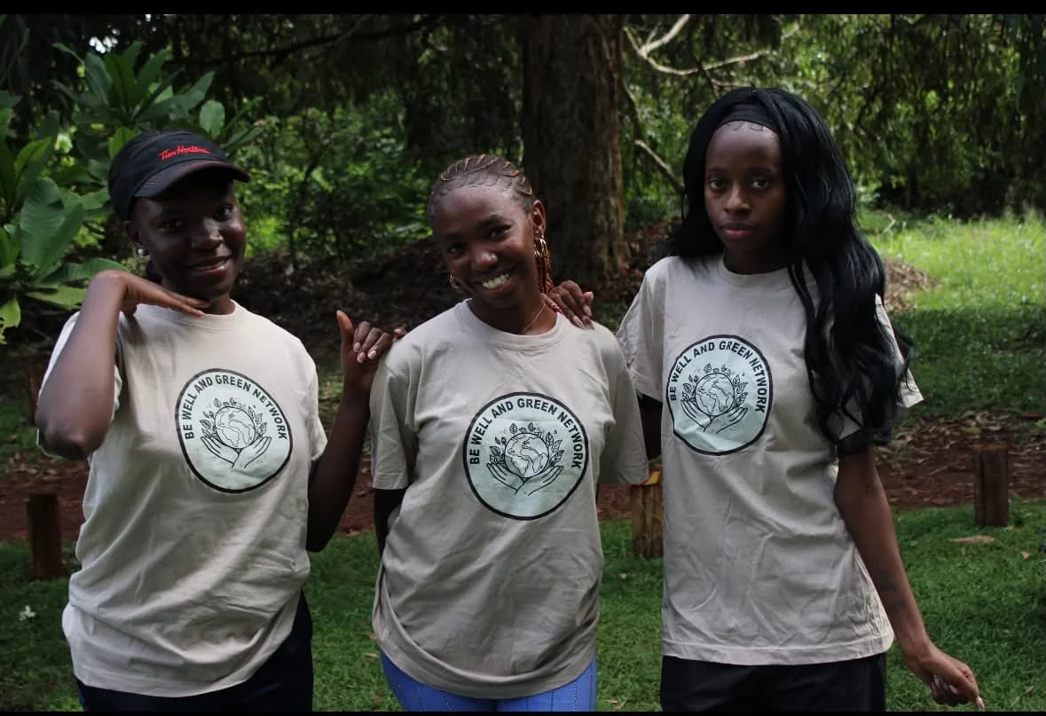 Three BWGN volunteers in branded T-shirts standing together in a green outdoor space