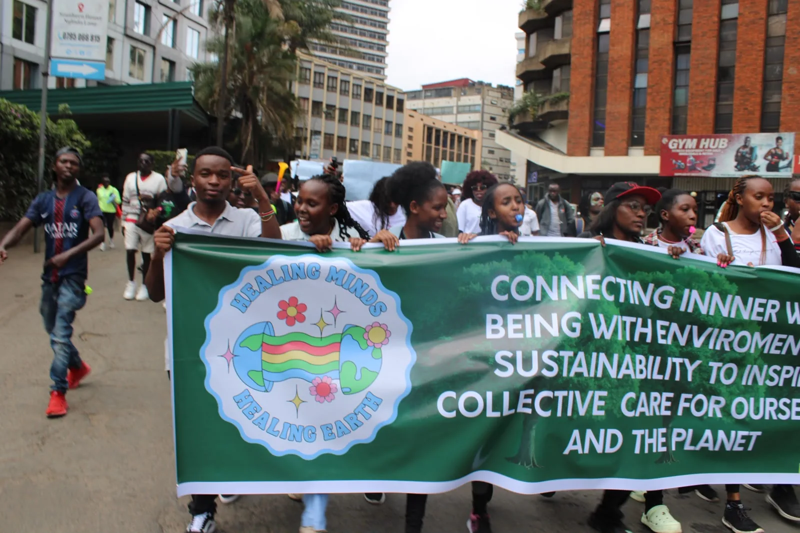 Youth volunteers holding a Healing Minds, Healing Earth banner during a street march